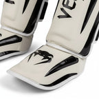 Pair of Venum shin guards on a gray background