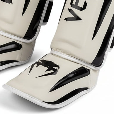 Pair of Venum shin guards on a gray background