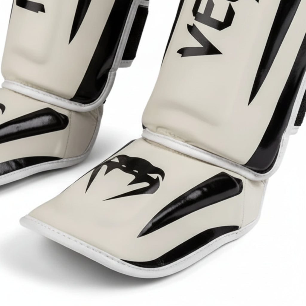 Pair of Venum shin guards on a gray background