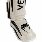 Beige shin guard with black logo on a gray background