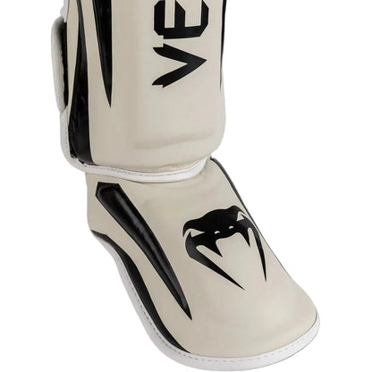 Beige shin guard with black logo on a gray background