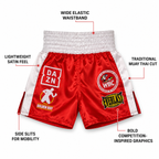 Red and white satin Muay Thai shorts with multiple brand patches, surrounded by callout lines and text describing features like the wide elastic waistband and side slits.