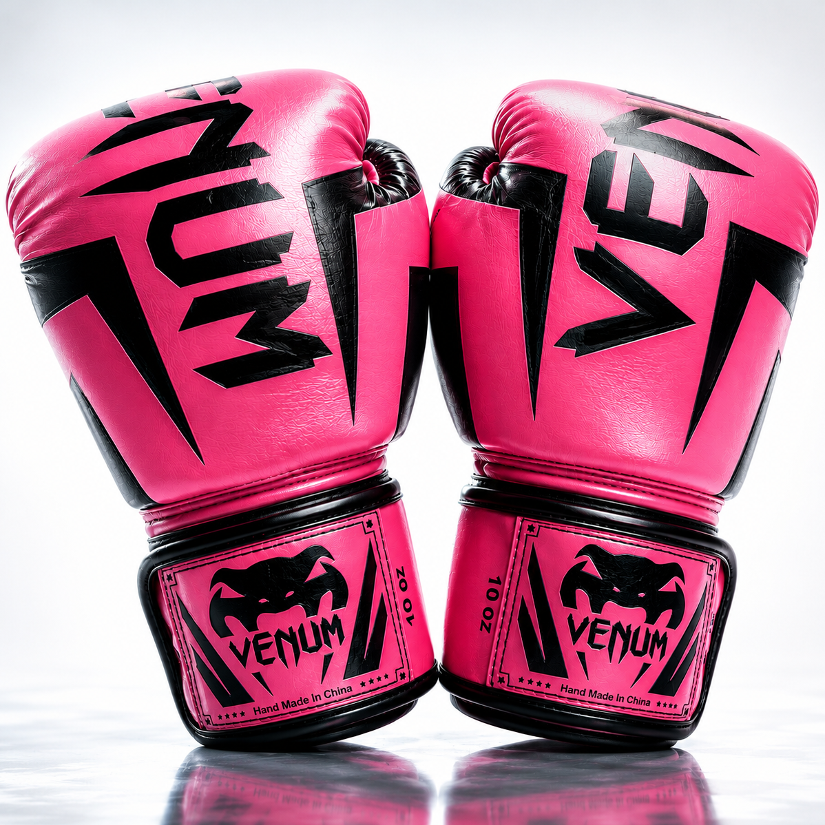 Pair of pink boxing gloves with black Venum branding on a reflective surface.