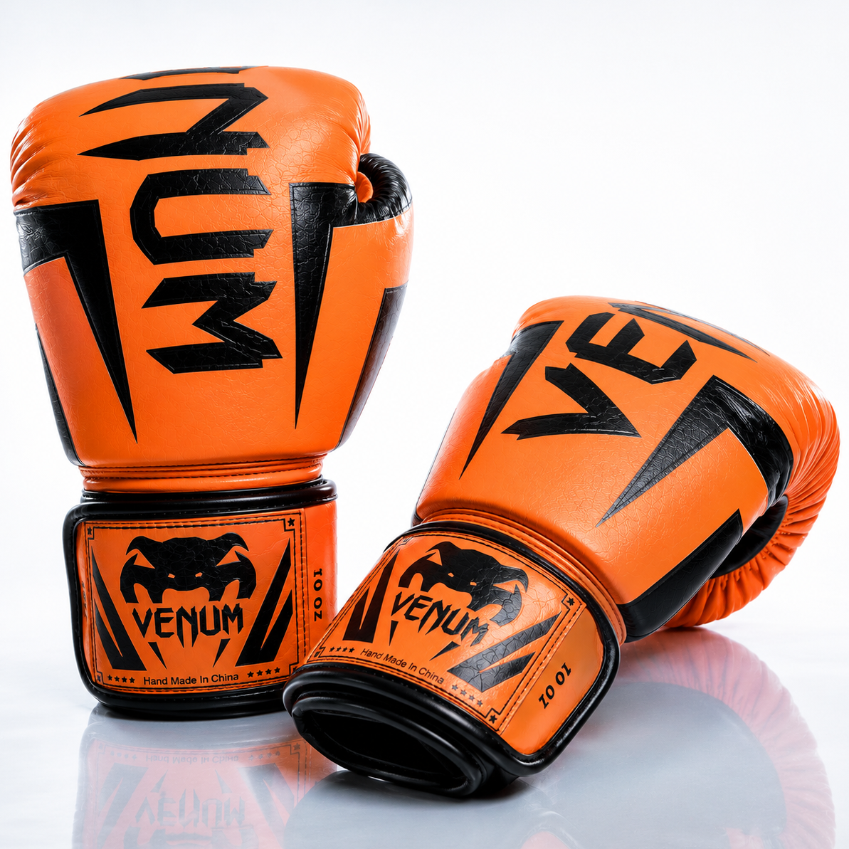 Orange boxing gloves with black logos on a reflective surface
