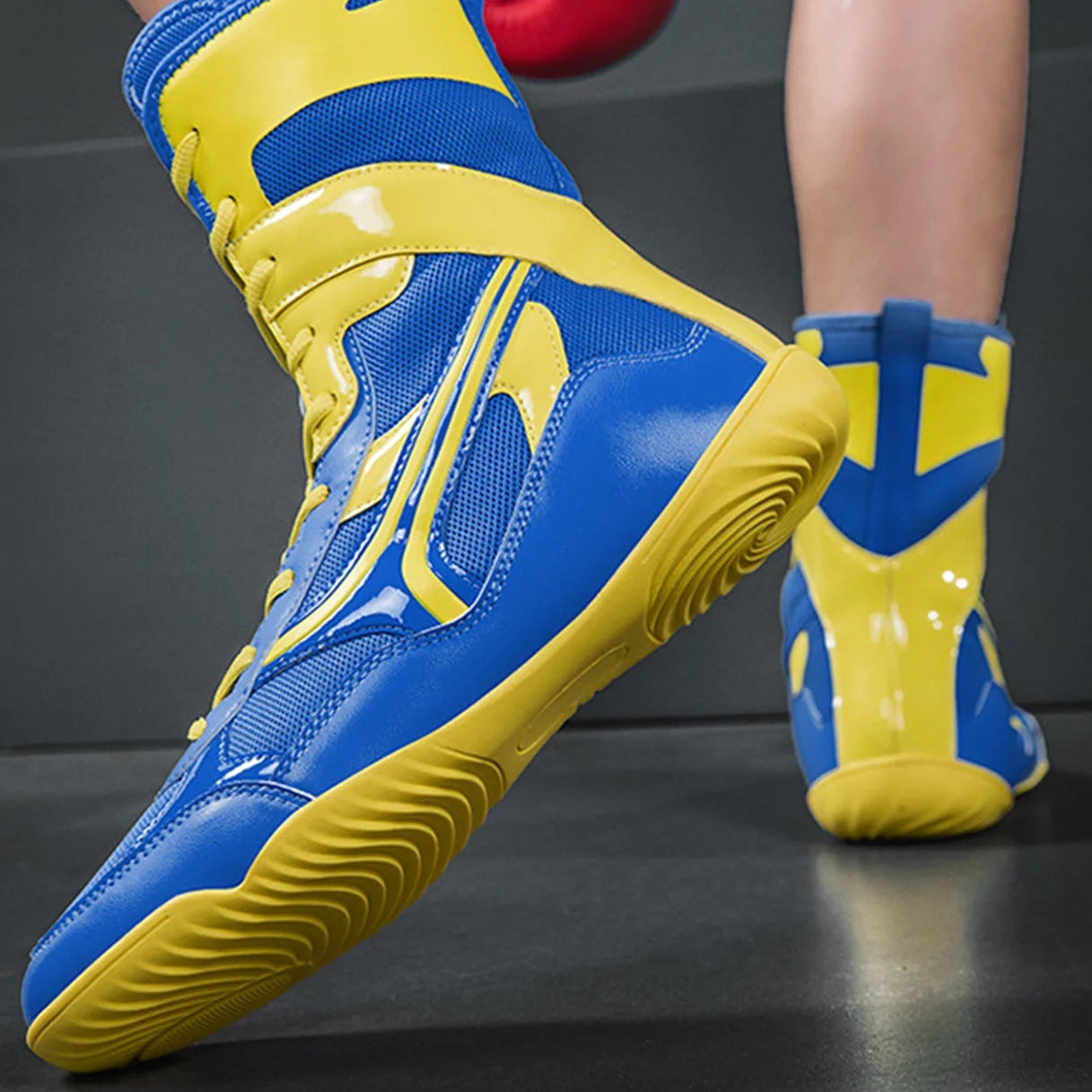 Blue and yellow boxing shoes worn with red boxing gloves on a dark background