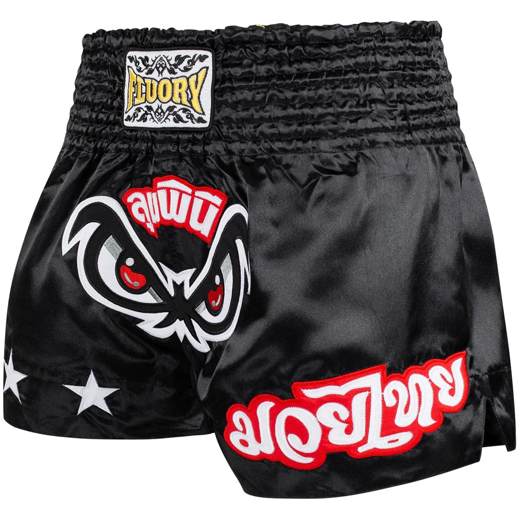 Black Muay Thai shorts with red and white designs on a white background, featuring the Fluory brand.