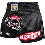 Black Muay Thai shorts with red and white designs on a white background, featuring the Fluory brand.