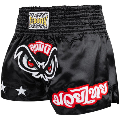Black Muay Thai shorts with red and white designs on a white background, featuring the Fluory brand.