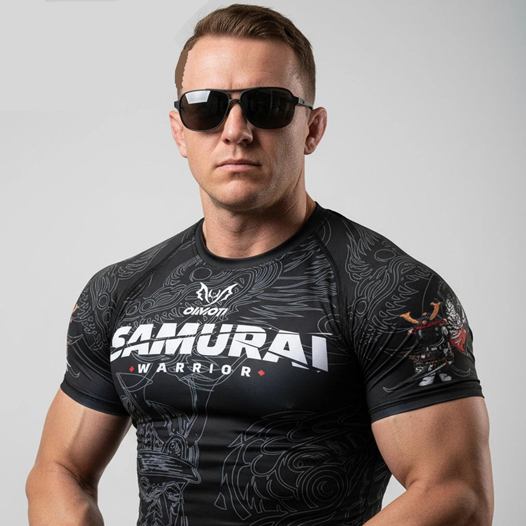 A muscular man wearing a black short-sleeve athletic rash guard with 'SAMURAI WARRIOR' printed on the chest, styled with black sunglasses. The OIMOTI brand logo is visible in the top left corner against a solid gray background.
