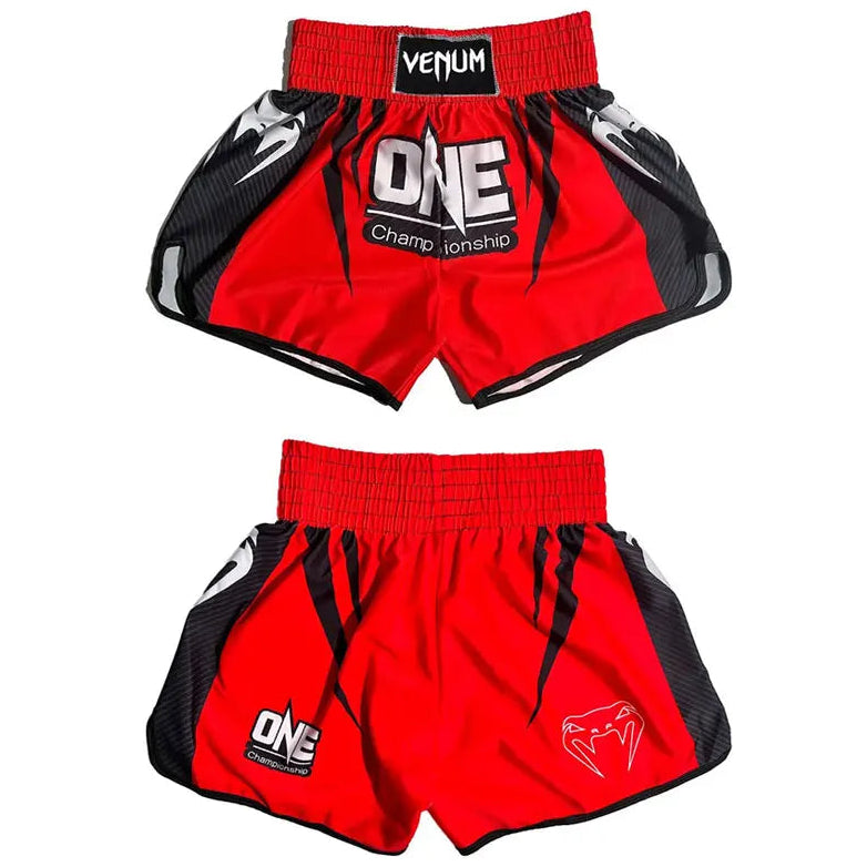 Two pairs of red and black Venum Muay Thai shorts displayed against a white background, showing both the front and back views. The front pair features a red waistband with a black Venum logo patch, a large 'ONE Championship' logo on the front, and black side panels with white graphic details.