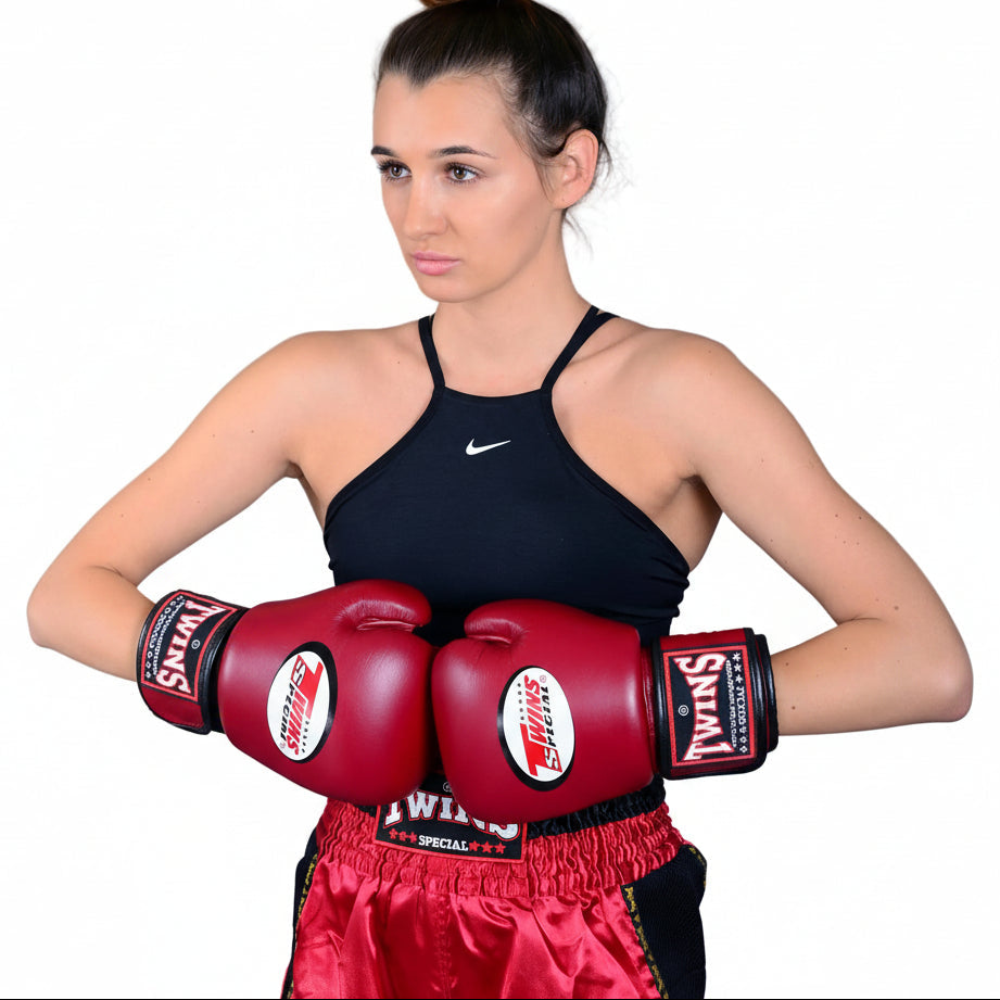 Woman in boxing gear with red gloves and shorts on a gray background