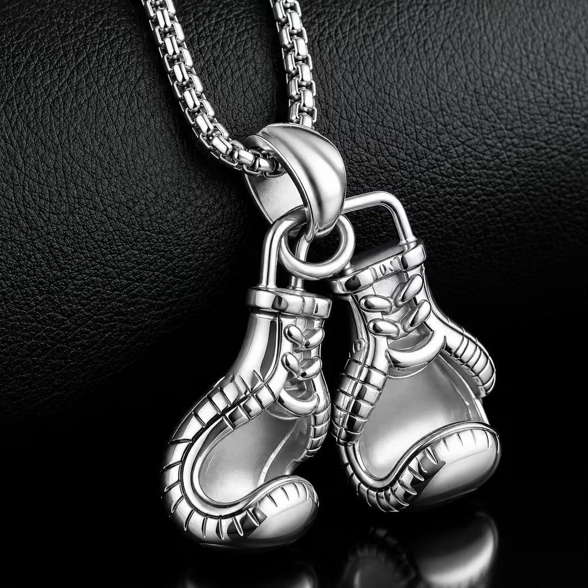 Silver boxing glove pendant on a chain against a dark background