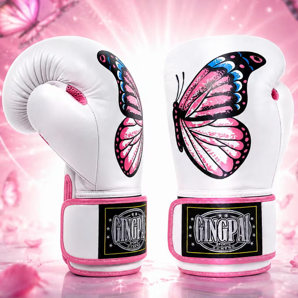 A pair of white boxing gloves with large pink, black, and blue butterfly designs on the back, featuring pink trim and a visible GINGPAI brand patch on the wrist area, set against a pink glittery background.