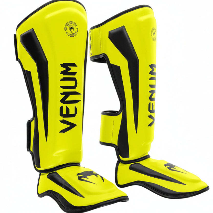 Yellow and black Venum shin guards on a white background