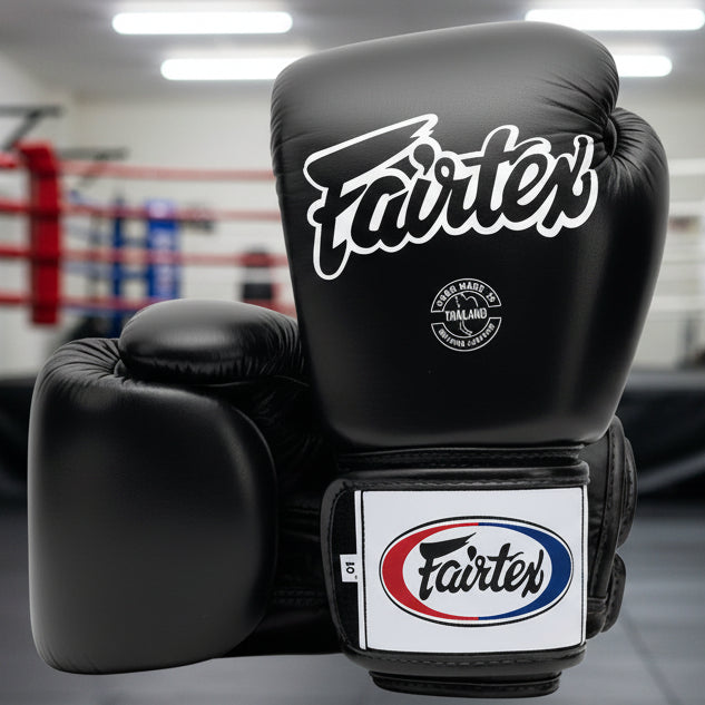 Black boxing gloves with Fairtex branding on a white background