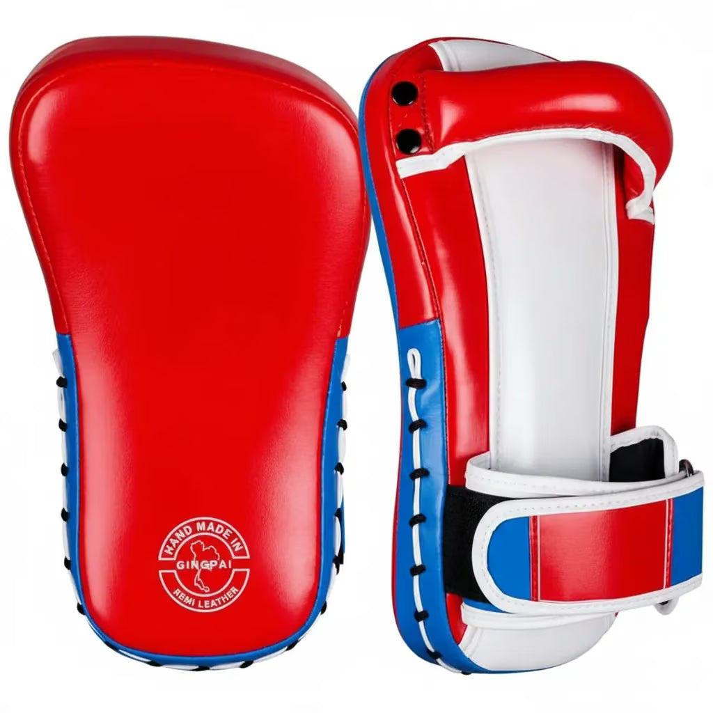 A pair of red, white, and blue kickboxing shin guards shown from the front and side angles against a plain white background. The brand logo 'GINKA' is visible on the lower left of the front guard.