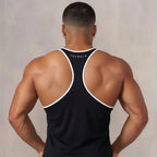 Man wearing a black tank top with white trim, standing against a plain background