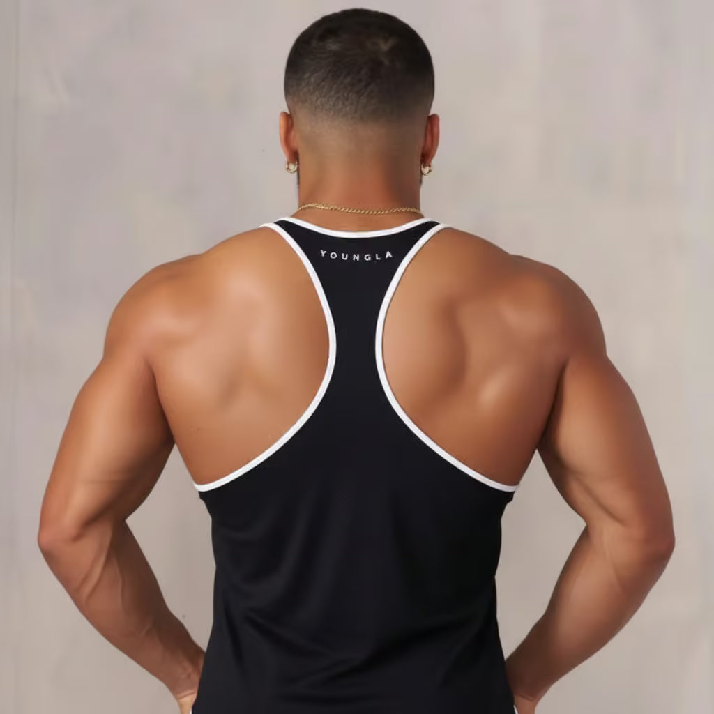Man wearing a black tank top with white trim, standing against a plain background