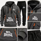 A dark gray and black Lonsdale hoodie with matching joggers, shown in a multi-view collage. The hoodie features a half-zip front, a large white Lonsdale London lion logo on the chest, and bright orange zipper accents.