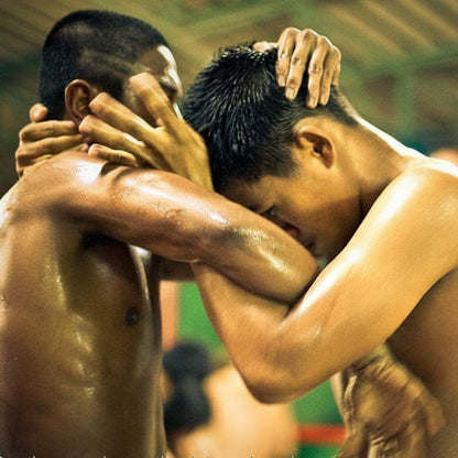 Two men thai clinching each other in a close-up shot, with a blurred background.