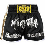 Black Muay Thai boxing shorts with white and silver graphic lettering, a yellow and black Glingpai waist patch, and gold side trim.