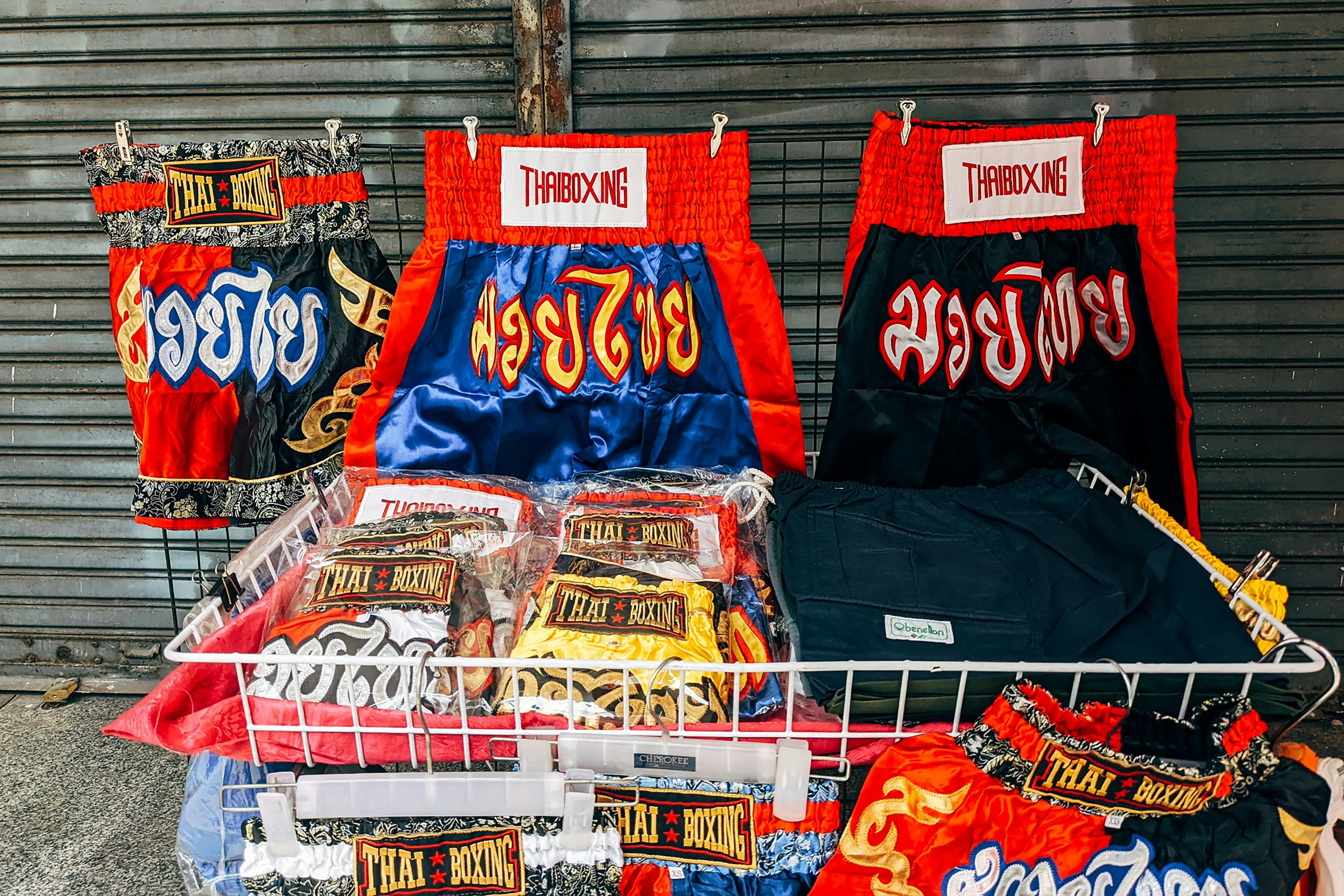 THAI BOXING merchandise including shorts and t-shirts displayed against a metal shutter.