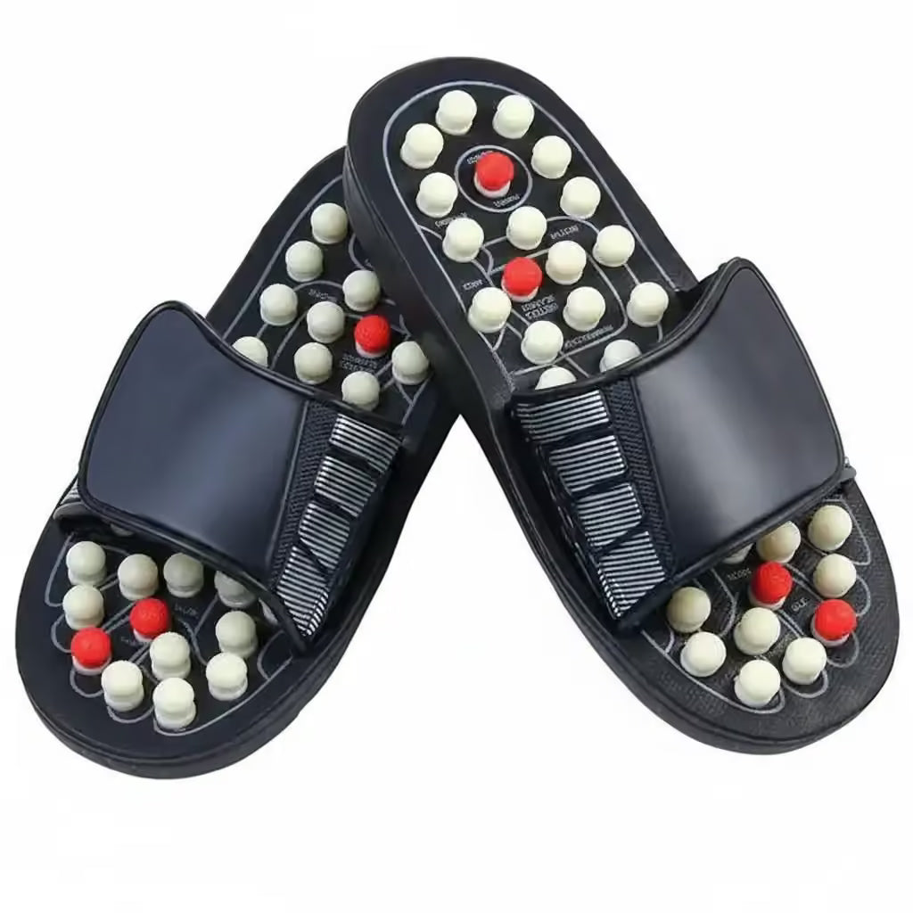 A pair of black slide sandals with massage nodes on the soles. The soles feature rows of small white and red spherical massage beads set into a black textured footbed, with a wide black strap across the top.