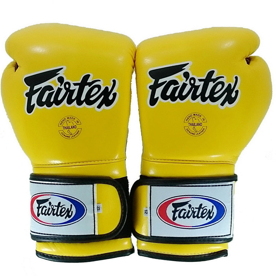 Pair of yellow Fairtex boxing gloves on a white background