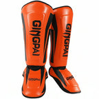 A pair of bright orange shin guards with black accents and the brand name 'GINGPAI' printed in black on the front, shown against a plain white background.