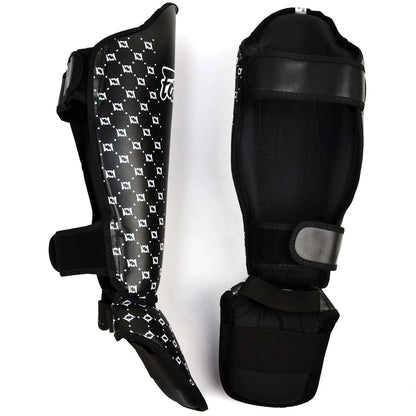 Black shin guards with patterned design on a white background