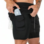 Person wearing black athletic shorts with a pocket holding an Apple device on a white background