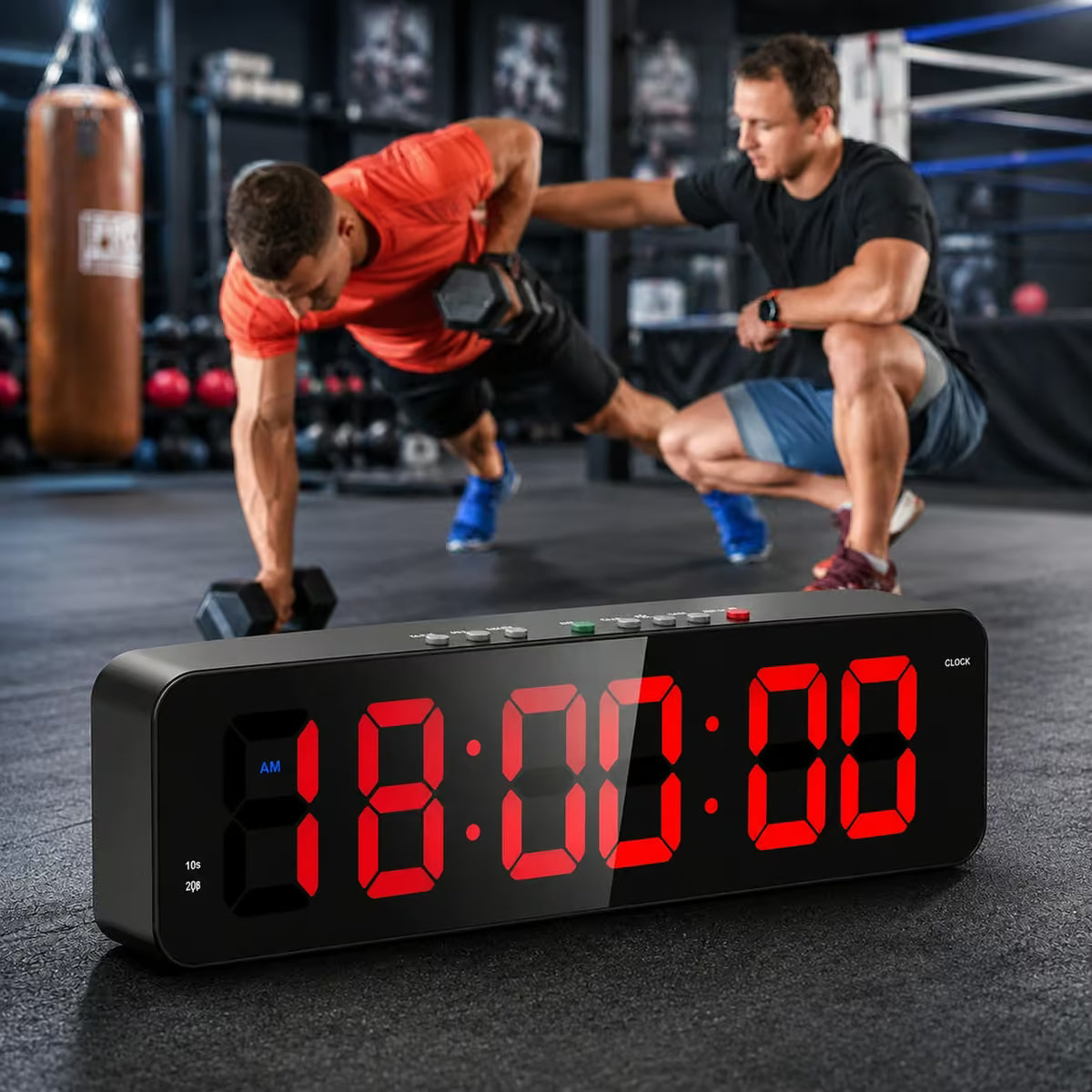A black digital workout timer with large red LED numbers sits in the foreground on a gym floor, with two men exercising in a boxing gym behind it.