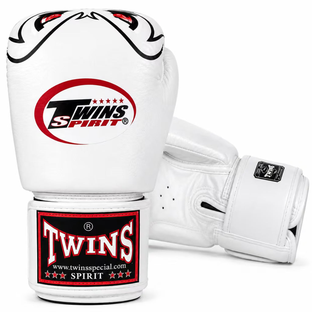 A pair of white Twins Spirit boxing gloves on a clean white background, showing the front glove with the large red and black Twins Spirit logo and the front strap label, plus the back glove showing the wrist strap.