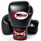 Three black leather boxing gloves, with one prominently displayed in the foreground showing the Twins Special logo on the knuckle and wrist strap, set against a clean white background.