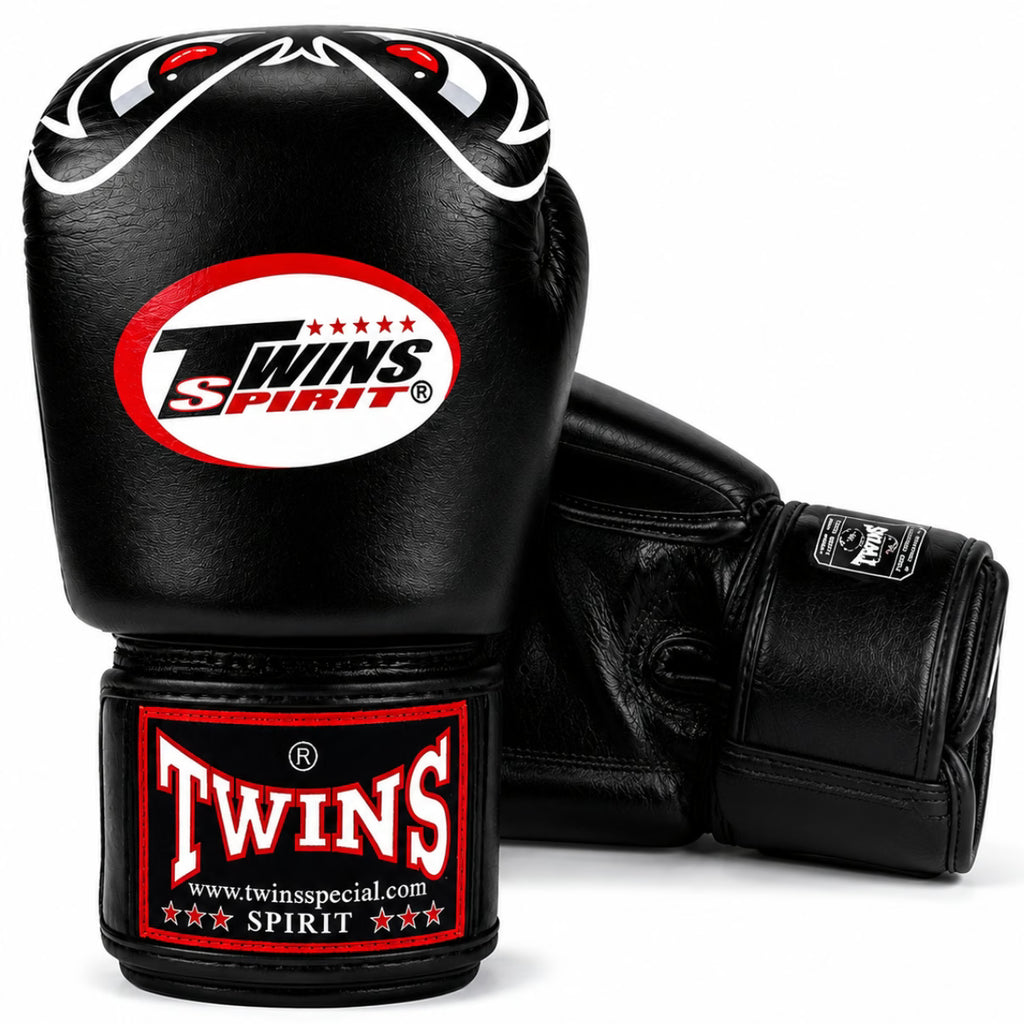 A pair of black Twins Spirit boxing gloves on a clean white background, showing the front glove with the main logo and the rear glove showing the wrist strap.