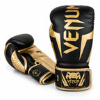 A pair of Venum boxing gloves in black and gold, displayed on a clean white background. One glove is positioned upright to show the front with the large gold Venum logo, and the other is angled to show the back and wrist strap with the Venum brand patch.