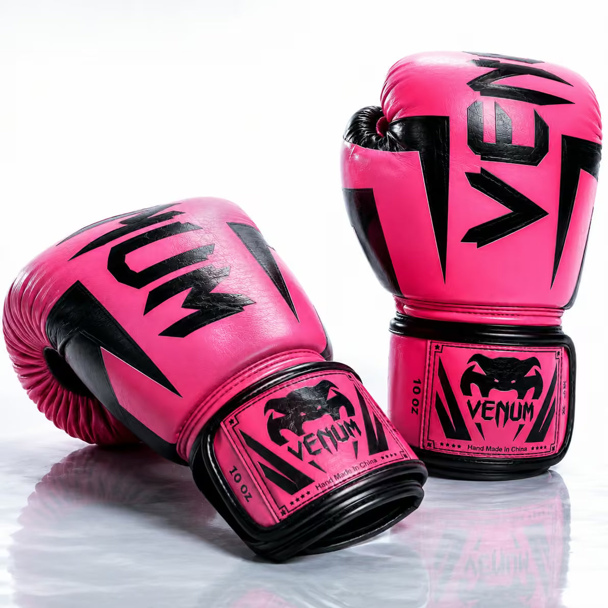 A pair of Venum 10 oz boxing gloves in vibrant pink with black accents, displayed on a reflective white surface.