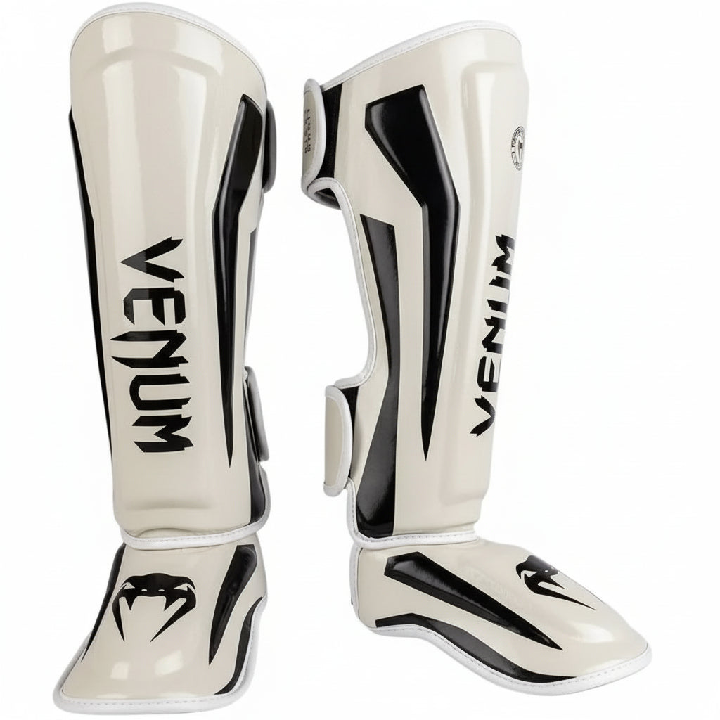 Pair of Venum shin guards on a gray background