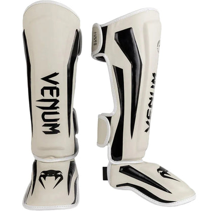 Pair of Venum shin guards on a gray background