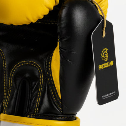 A pair of Pretorian boxing gloves in yellow and black, shown against a light gray background with promotional text and care instructions. The gloves feature a bold black logo and branding, and the image includes text detailing the product options and care guidelines.